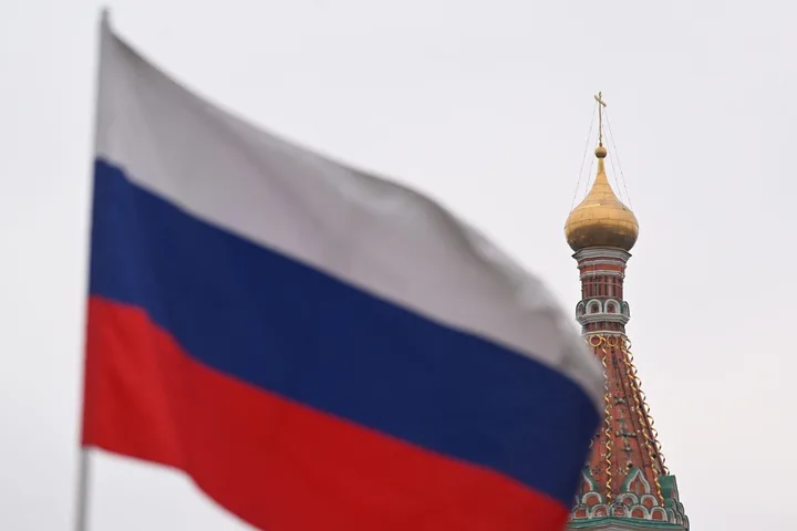 Steagul Rusiei în prim-plan, cu o biserică în fundal.