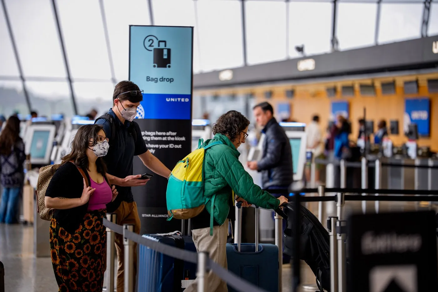 Călători la aeroport, purtând măști de protecție.