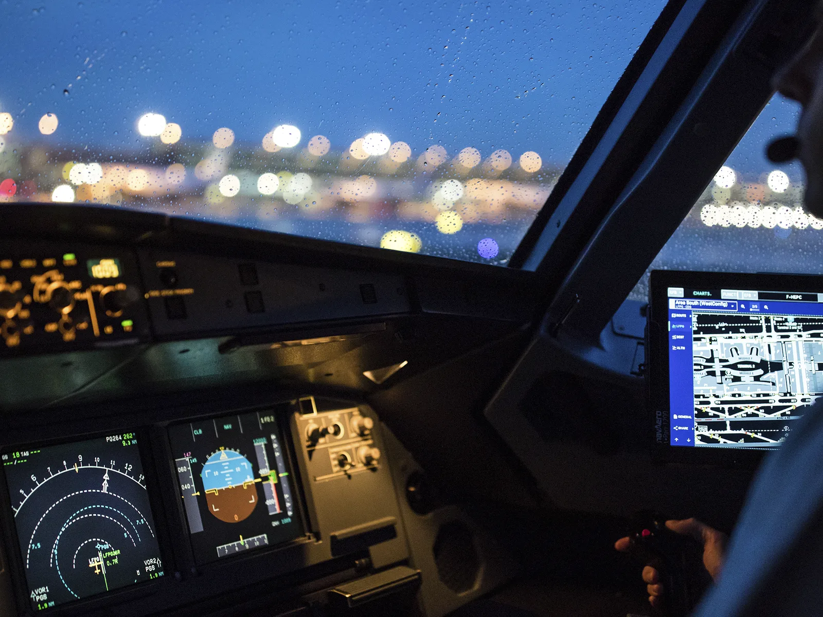 Cabina de pilotaj a unui avion în timpul nopții, cu ecrane luminoase.
