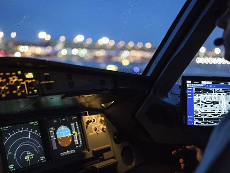 Cabina de pilotaj a unui avion în timpul nopții, cu ecrane luminoase.
