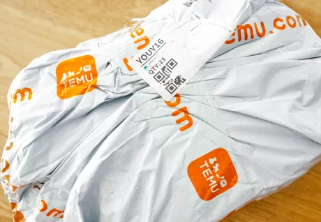 Pachet livrat de Temu, ambalat în folie gri, cu etichete portocalii.