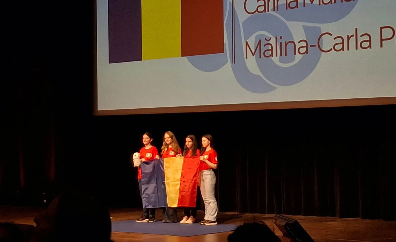 Echipa română de fete la Olimpiada Europeană de Matematică, cu medalii și steagul României.