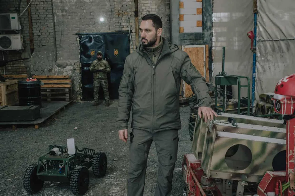 Ofițer militar ucrainian lângă un robot de luptă în hangar.