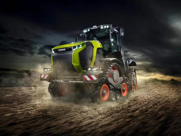 Tractorul CLAAS XERION 12 în acțiune pe câmp, cu șenile și iluminare modernă.