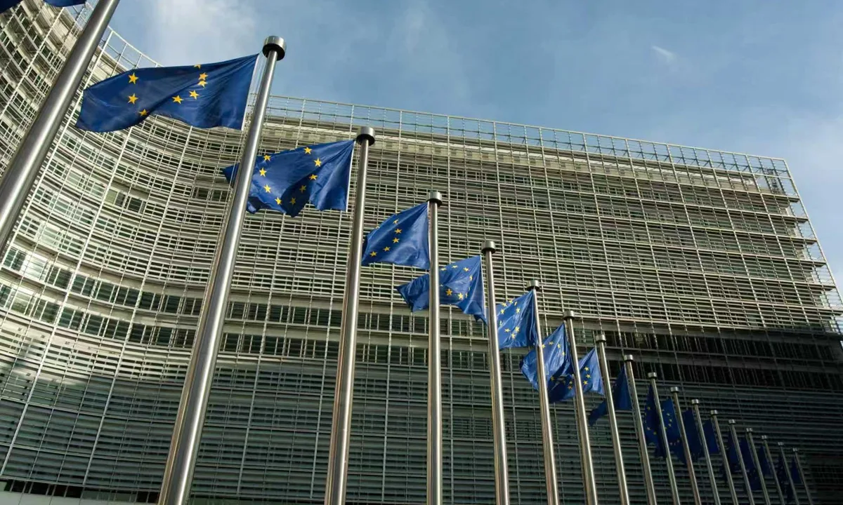 Clădirea Comisiei Europene cu steaguri ale Uniunii Europene în față.