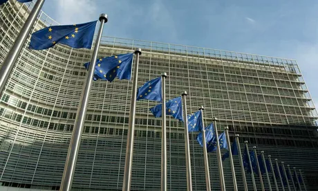 Clădirea Comisiei Europene cu steaguri ale Uniunii Europene în față.