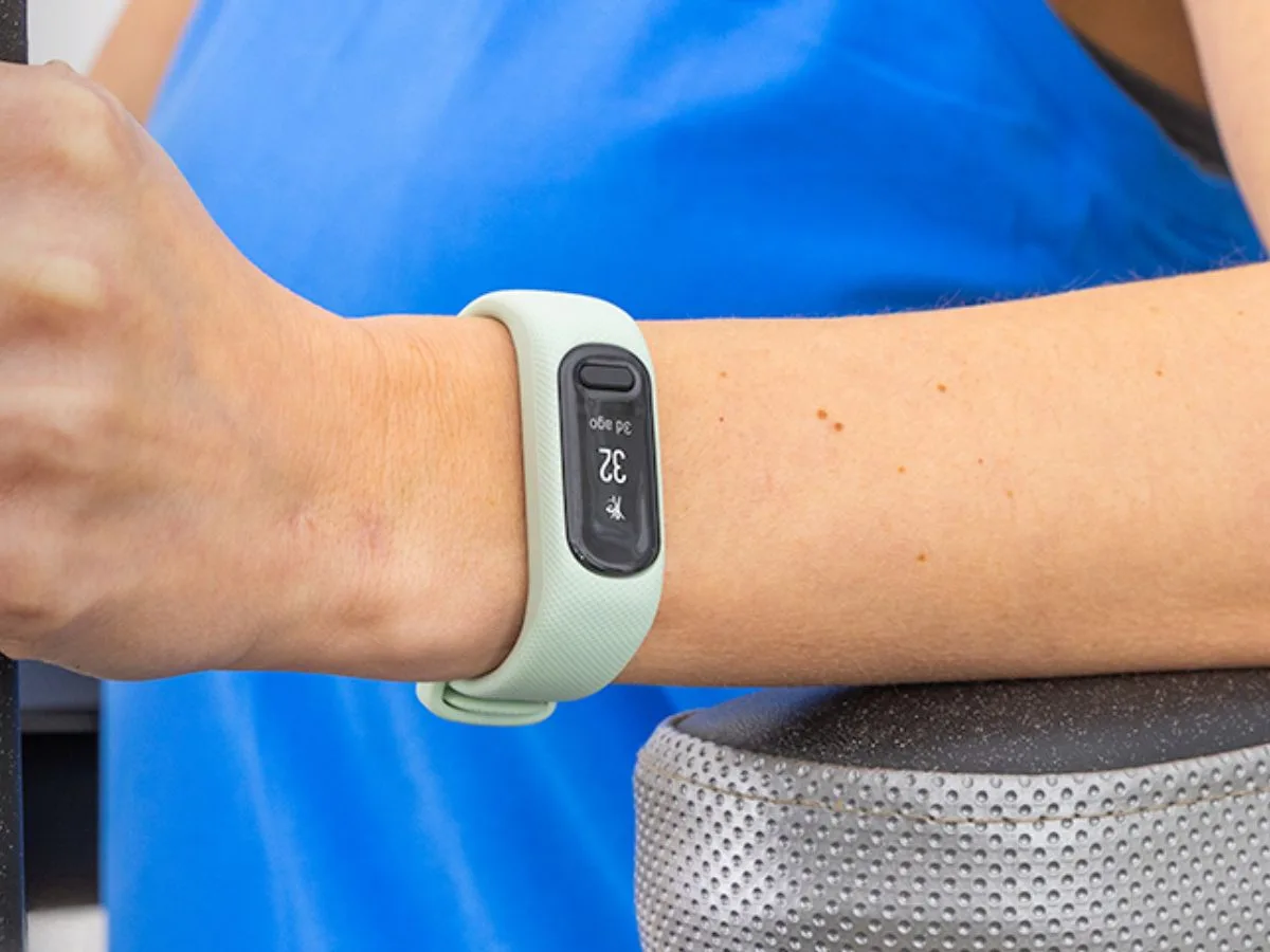 Brățară de fitness Garmin Vivosmart 6 pe încheietura unei mâini, cu ecran activat.