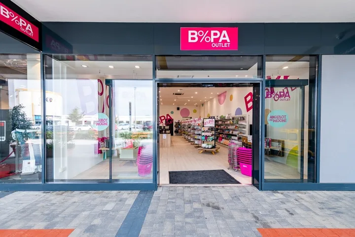 Intrarea unui magazin BIPA, cu produse diverse pe rafturi.