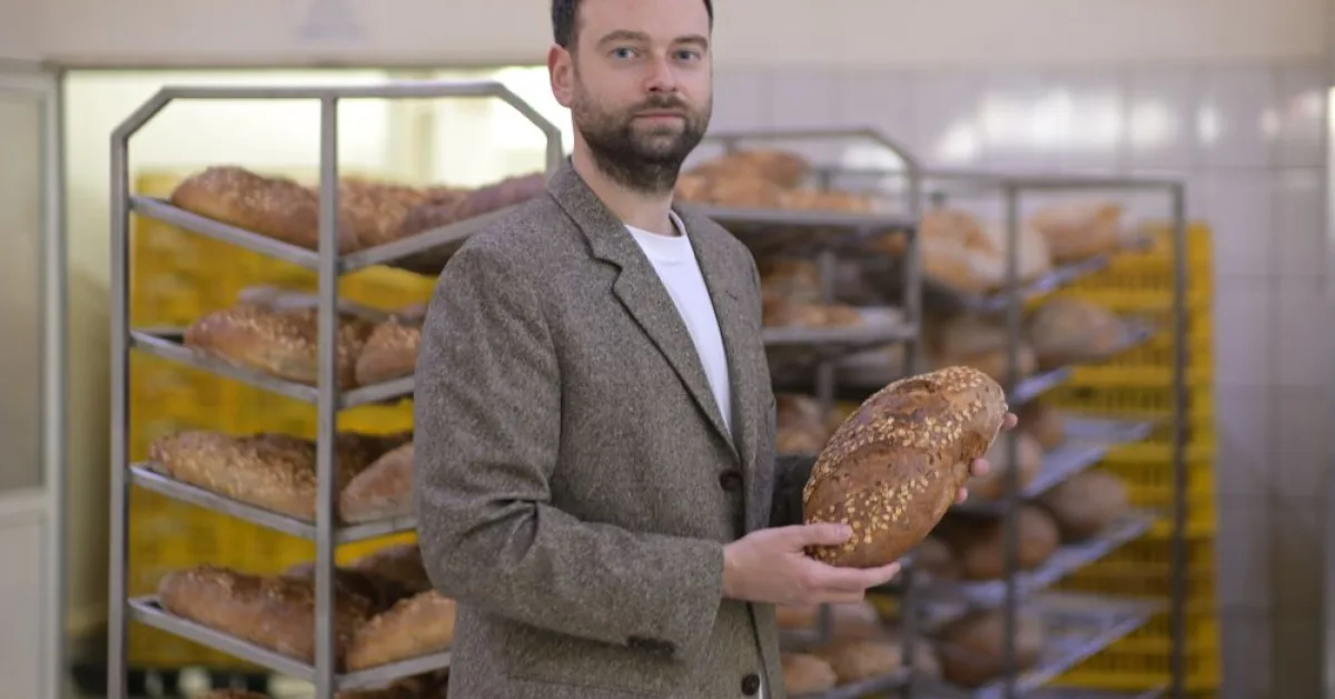 Un bărbat ținând o pâine artizanală într-o brutărie modernă.