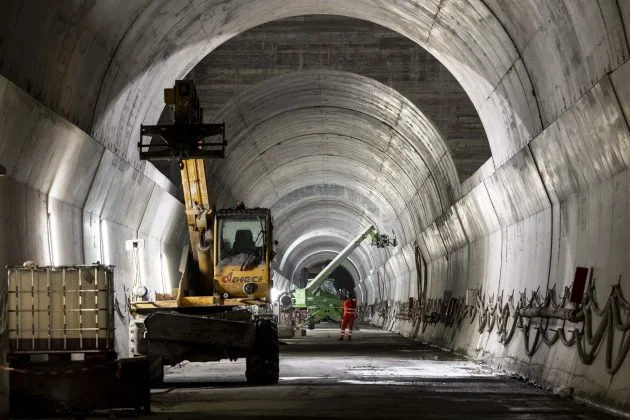 Tunelul Brenner în construcție, cu utilaje de forare și muncitori.