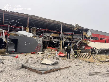 Clădire distrusă în urma atacurilor, cu echipaje de intervenție la fața locului.