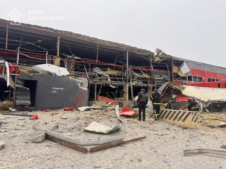 Clădire distrusă în urma atacurilor, cu echipaje de intervenție la fața locului.