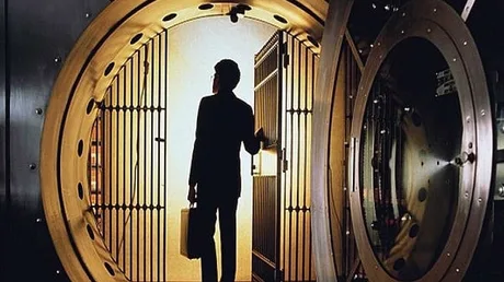 Persoană într-o bancă, reflectând asupra reglementărilor financiare stricte.