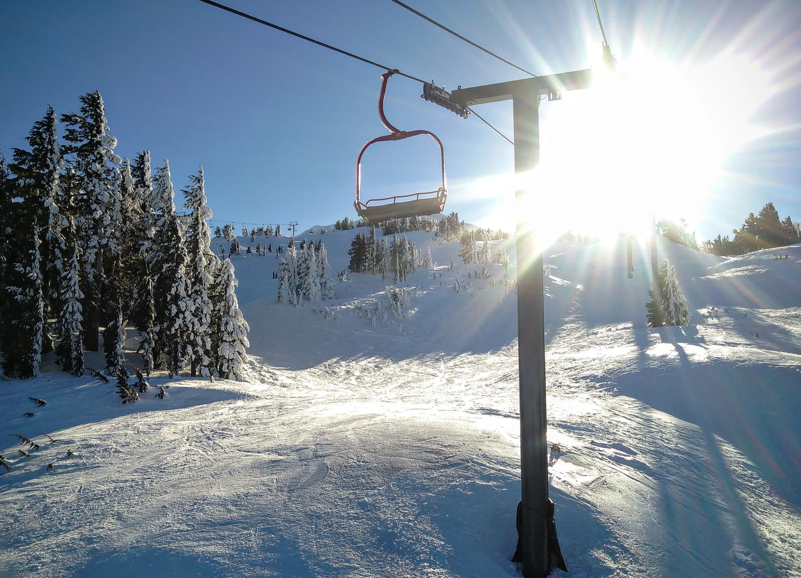 Peisaj montan cu zăpadă și soare strălucitor, pregătit pentru schi.