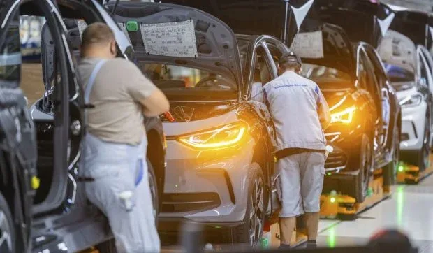 Lucrători asamblând automobile într-o fabrică Volkswagen.