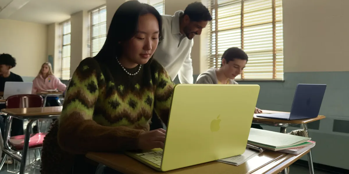 Studenți folosind MacBook Neo într-o sală de clasă modernă.
