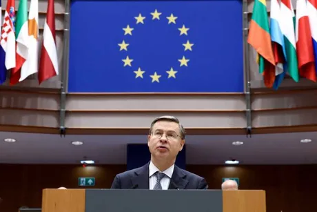 Valdis Dombrovskis susține un discurs în fața steagului Uniunii Europene.