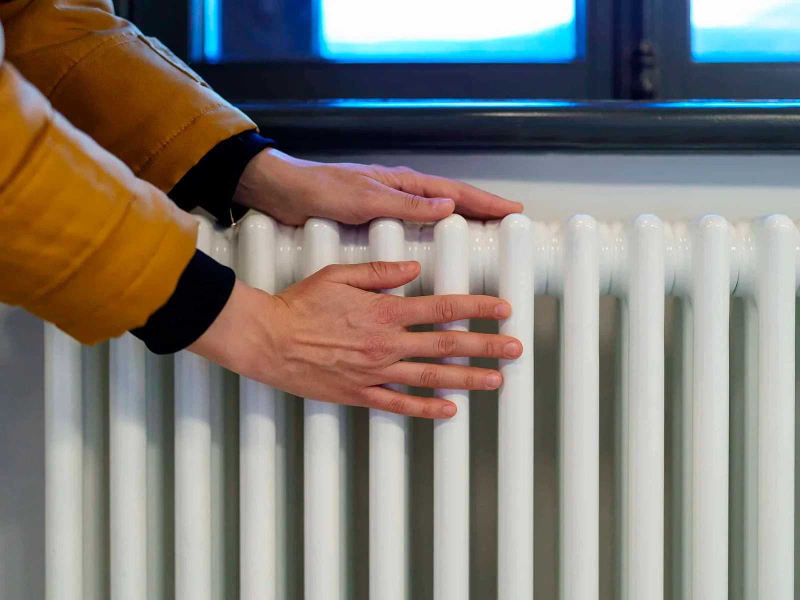 Persoană verificând un radiator pentru încălzirea locuinței.