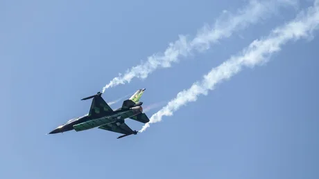 Avion F-16 românesc în zbor, cu urme de vapori în aer.